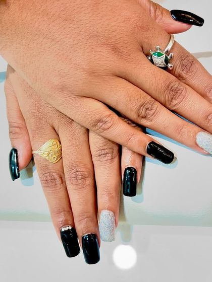 A chic and modern design featuring glossy black square-shaped nails with a silver glitter accent nail and subtle rhinestone details.