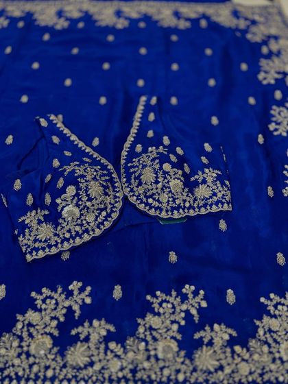 Another look at the detailed craftsmanship on our party wear collection. This royal blue blouse features delicate floral embroidery that extends across the sleeves, designed to complement the matching Chinon saree.