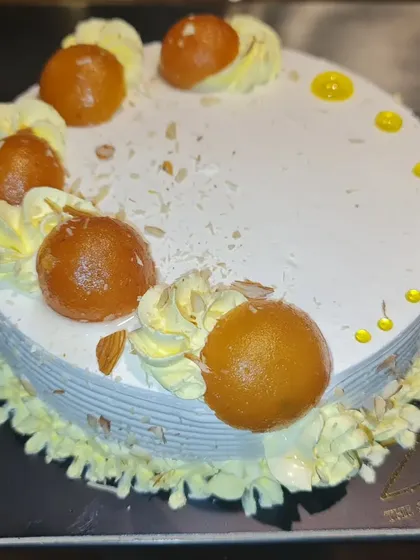 A delicious example of my Indian fusion cakes. This cake is topped with soft, syrup-soaked Gulab Jamuns and garnished with nuts, blending the traditional Indian sweet with a classic vanilla cream cake for a unique flavour experience.