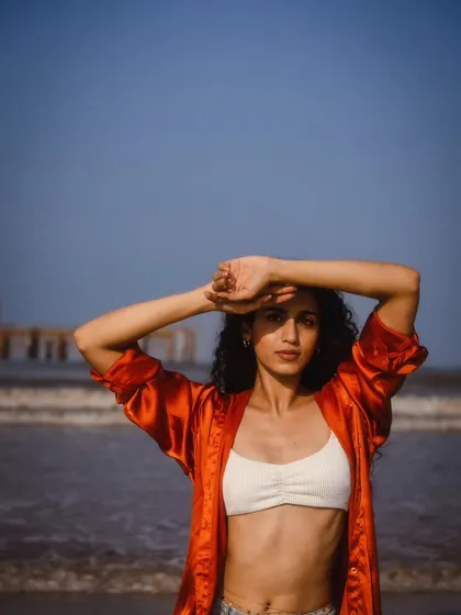 A simple, direct portrait against the sea and sky. The pose is natural, shielding her eyes from the sun, which makes it feel very relatable.