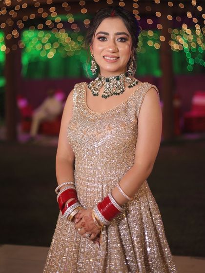 The bride stands against a backdrop of green and white lights, her glittering dress shining in the festive lighting.