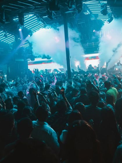 A wide shot of the packed dance floor at a club in Goa, with smoke filling the air.