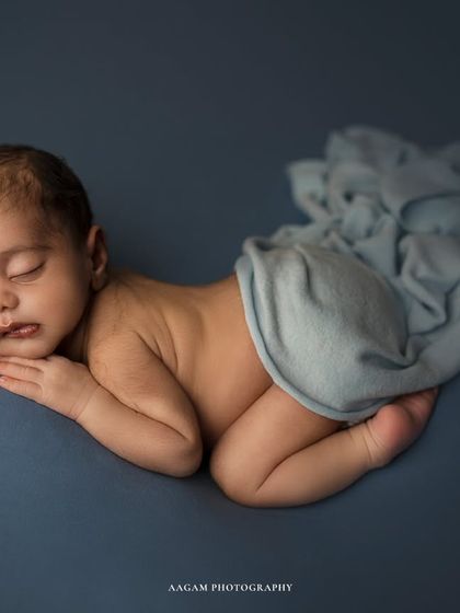 A full-body view of the same baby, curled up in a natural, womb-like position. The gentle draping of the fabric adds a touch of artistry.