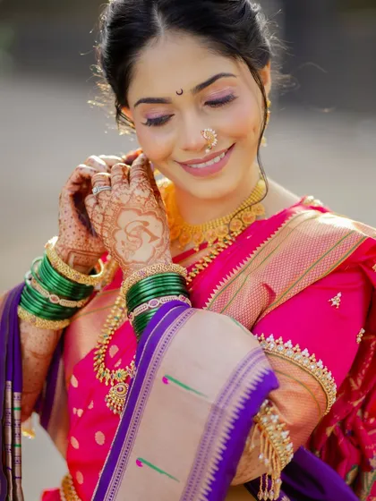 A candid moment showing the intricate details of the bride's henna and the traditional green bangles against her vibrant pink saree.