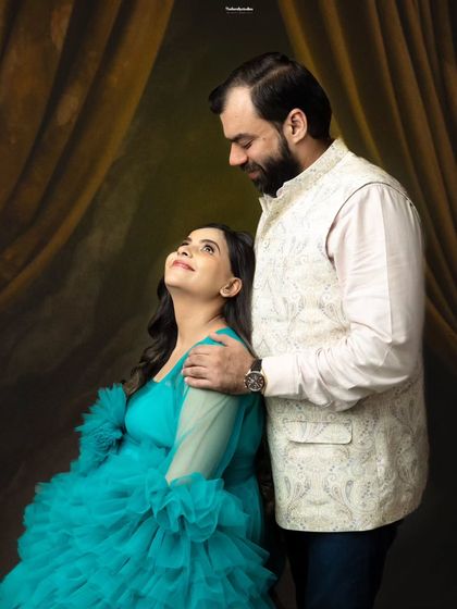A beautiful couple's portrait featuring a vibrant turquoise gown and a classic Nehru jacket. We help coordinate outfits to create a cohesive and visually stunning look for your pregnancy photoshoot.