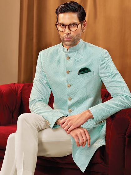 A moment of quiet confidence. This light aqua bandhgala jacket, crafted from a subtly patterned fabric, is paired with classic white trousers for a fresh and elegant look.