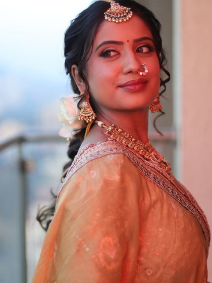 A candid, over-the-shoulder glance from the bride. The warm, golden hour lighting perfectly complements her dewy makeup and the color of her outfit.