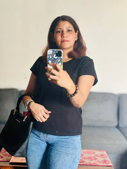 A mirror selfie at home in a basic black t-shirt and jeans, the foundation of many great outfits.