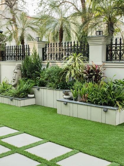 A well-curated garden tells a story. In this front yard, we used tiered planters to create depth and layered various plants and sculptures to reflect the client's vision, turning a simple lawn into a curated green space.