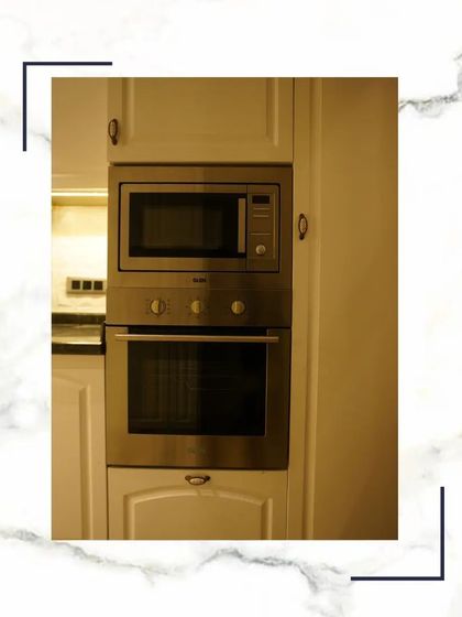 A close-up of the built-in stainless steel microwave and oven. We use trusted brands to ensure your kitchen is equipped with reliable and stylish appliances.