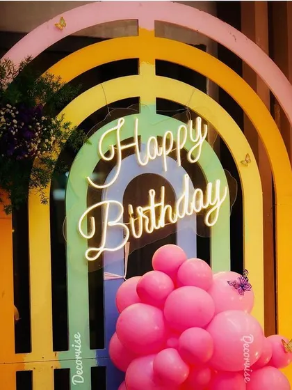 A closer look at the rainbow and butterfly birthday backdrop. The small butterfly details and fresh floral accents on the pastel-colored arches add a delicate and charming touch to the overall design.