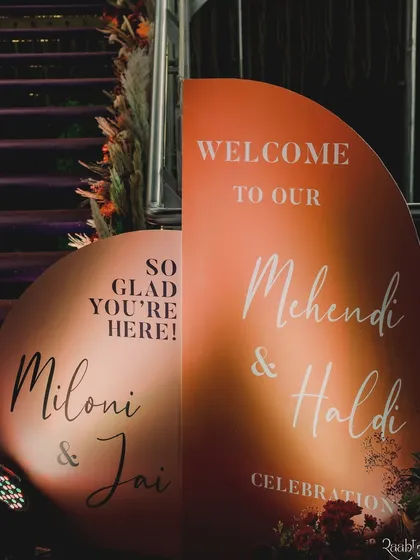 The custom welcome signage for the Mehendi and Haldi, designed with a modern arch shape and warm terracotta colors.