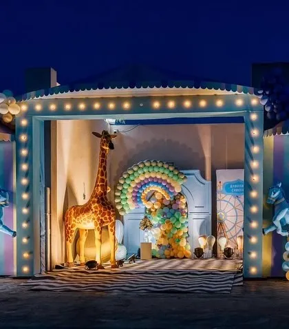 Step right up to this spectacular carnival-themed celebration. This large-scale outdoor setup at night shows our ability to create immersive experiences with elements like carousel horses, a giant giraffe, a Ferris wheel prop, and vibrant lighting.