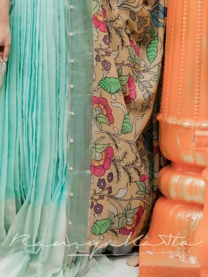 A detail shot of the pleated sea blue chanderi silk lehenga skirt next to the vibrant, hand-painted Kalamkari dupatta.