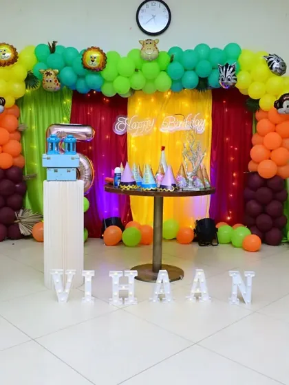 A wild jungle-themed 5th birthday for Vihaan. The decor features a colorful balloon arch with animal foils, a vibrant backdrop, and jungle-inspired props for a fun safari adventure.