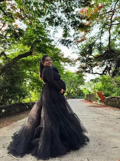 This black tiered gown combines comfort and style with its full-sleeved top and voluminous net skirt. It's a versatile piece that works for both studio and outdoor shoots.