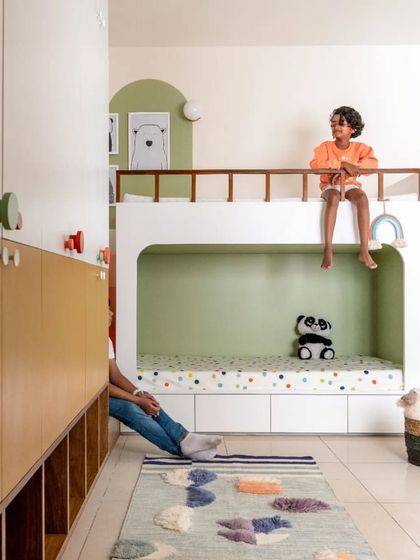 The kids' room is a space for both rest and play. The upper bunk provides a cozy perch, while the floor area is kept open with a colorful rug.