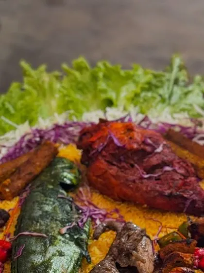 A platter of our Arabian-style grilled chicken and fish, served on a bed of flavored rice and garnished with fresh salads.