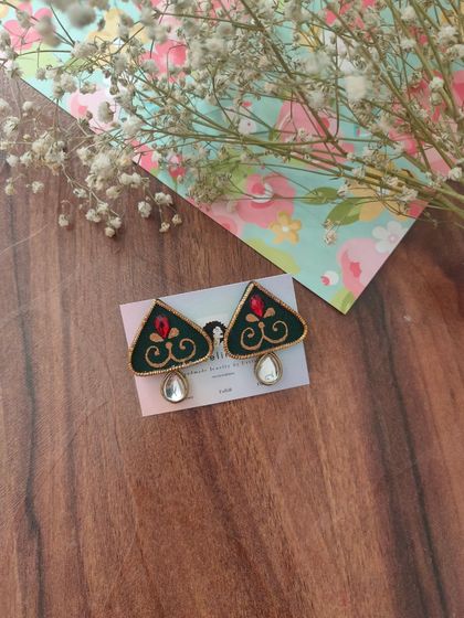 A pair of hand-painted earrings in a unique triangular shape. The dark green fabric is decorated with a red and gold motif and a single mirror drop.