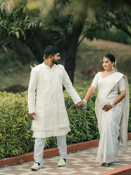 A classic walking shot of the couple holding hands, dressed in elegant white. This timeless portrait highlights their connection and the simplicity of their love.