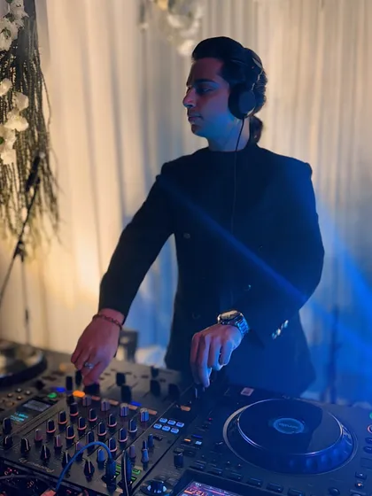 Pose on point. A moment of confidence behind the decks, ready to drop the next track for a wedding party.
