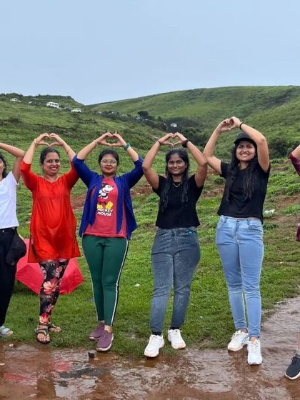 A group of friends making a heart shape with their hands, showing their love for the beautiful landscapes of Chikmagalur.