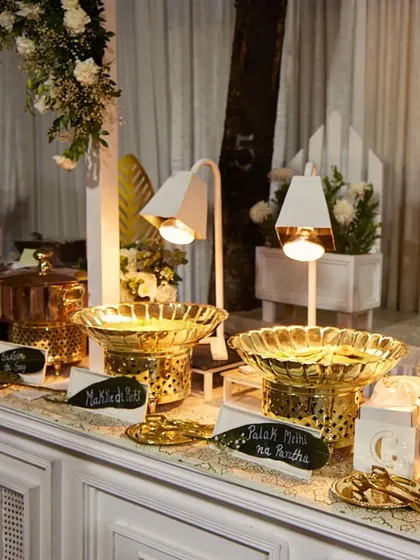 A beautifully lit buffet station with golden serving dishes. The warm lighting highlights the food and creates an inviting glow, enhancing the overall dining experience.