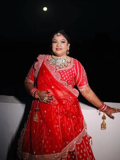 A full-length shot of the bride against the night sky, looking absolutely regal in her red lehenga.