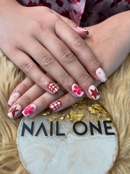 Another view of the mismatched red and pink nail art, showing how different designs on each nail can create a cohesive and fun overall look.