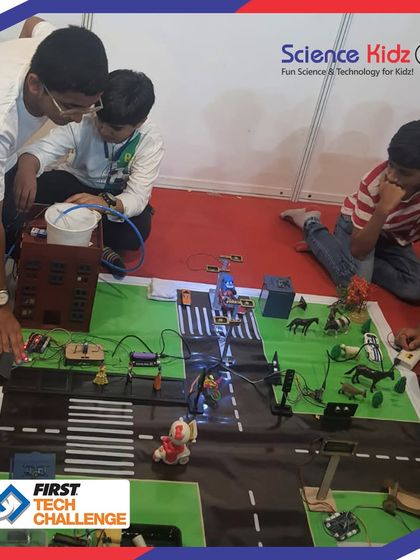 Students making final adjustments to their smart city model before the judges' evaluation at the First Tech Challenge. This image shows the intricate wiring and placement of components like Arduino boards and sensors.