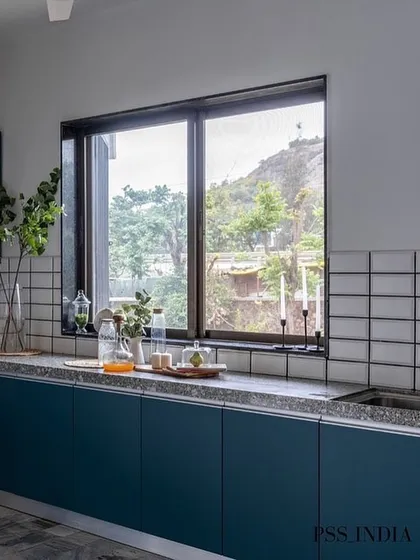This kitchen features beautiful teal blue cabinets and a simple white tiled backsplash. The large window offers a lovely view and fills the space with natural light, making it a pleasure to cook in.