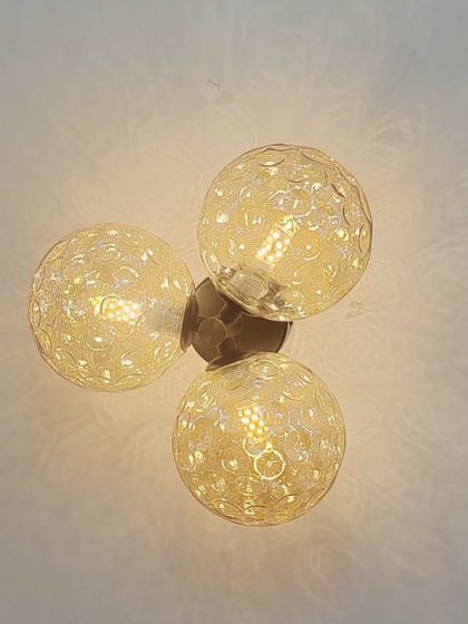 A close-up of a wall or ceiling light with three textured amber glass globes.