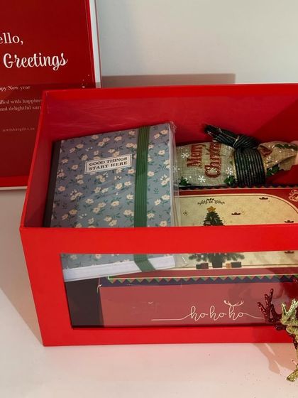 An open view of our New Year hamper, revealing a journal, a small bottle of wine, and other festive goodies inside.