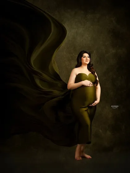 This portrait uses dramatic lighting and a flowing olive green fabric to create a painterly, fine-art feel. The dark, textured background makes the subject and the gown's movement stand out beautifully.