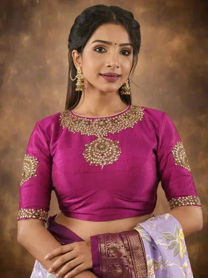 This magenta raw silk blouse is designed for grand celebrations. The neckline and sleeves are heavily adorned with intricate Zardosi and beadwork, creating a jewel-like effect. It’s a ready-to-wear piece that brings instant festive elegance to your ensemble.
5