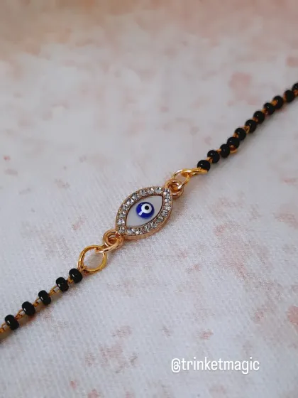 A detailed shot of the classic evil eye charm on my mangalsutra bracelet. The sparkling stones around the eye add a touch of glamour.