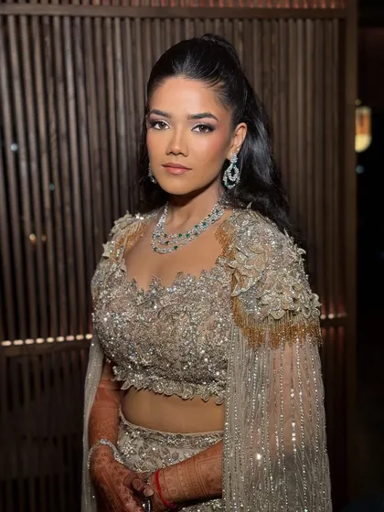 A sultry and luminous cocktail look designed for dusky skin tones. This makeup channels a radiant, high-fashion energy with glowing highlights and warm tones to beautifully complement a jeweled gold ensemble.