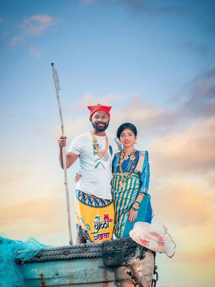 An iconic pose from an Agri-Koli pre-wedding shoot. The couple stands together in a boat against a beautiful sky, capturing the spirit of the Koli community and their connection to the sea.