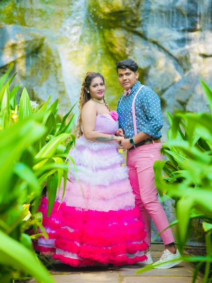 This fun and colorful pre-wedding photo showcases a playful couple's style. The tiered pink and white gown coordinates perfectly with the partner's pink trousers and suspenders.