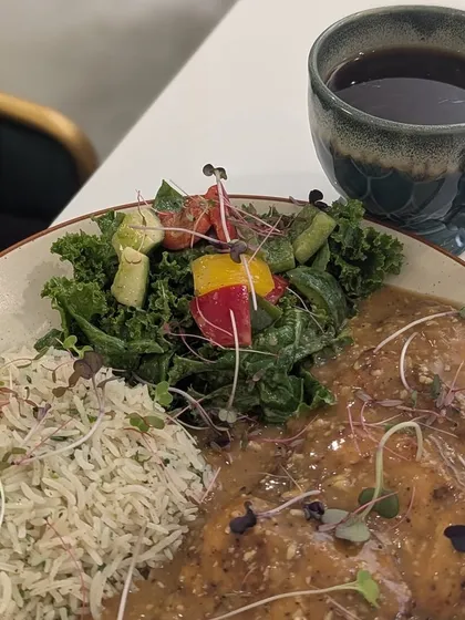 A healthy and visually appealing meal of grilled chicken in sauce, rice, and a fresh salad, paired with black coffee. Eating out can be healthy if you make smart choices.