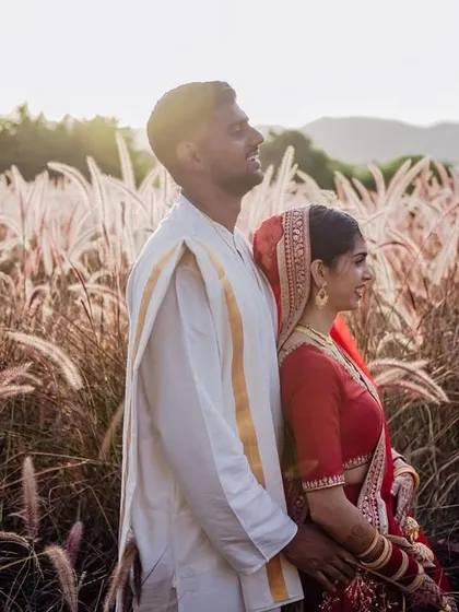 A beautiful portrait of the couple standing back-to-back in a field, bathed in the golden light of the setting sun.