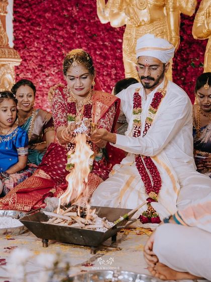 A couple participating in a traditional homa (fire ritual) during their South Indian wedding ceremony.