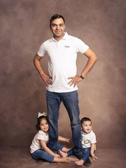 A fun and playful pose with dad and his two little ones. The children peek out from behind their father's legs, creating a photo full of laughter and personality.