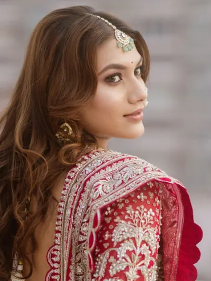 A beautiful side profile of my bride, ready for her pheras. Her soft, wavy hair is left open, and the makeup features a dramatic winged liner and a bold red lip.