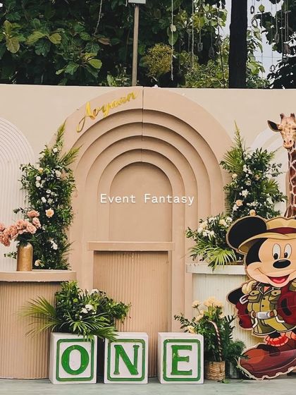A unique Mickey Mouse safari theme for Avyaan's first birthday. This setup blends the classic safari animals like a lion and giraffe with cutouts of Mickey Mouse dressed as an explorer, set against a modern, arched backdrop.