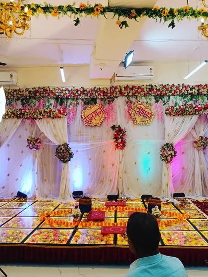 A stage being set up for a wedding function. This view shows the grand 'maharaja' chairs, the floral backdrop, and the spacious LED dance floor, ready to host the main event.