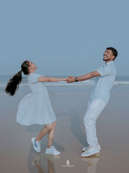 A joyful, leaning dance on the beach. The reflection in the wet sand adds a beautiful symmetry to this fun-filled shot.