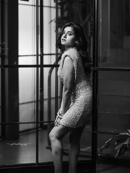 A black and white glamour shot that plays with light and shadow. By removing color, the focus shifts entirely to the model's expression, the form of her pose, and the texture of the glitter dress. This monochrome style adds a timeless, artistic quality to any portfolio.