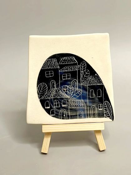 A square ceramic tile with a charming, hand-carved illustration of a village. These tiles add a touch of elegance and charm to any room in your home.