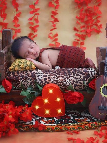 A little musician sleeping on a tiny bed. The red roses, heart light, and ukulele prop create a romantic and sweet musical theme for this baby boy's newborn session.